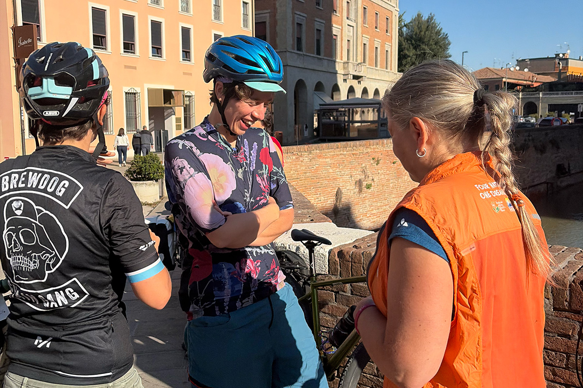 Tre cicliste sul ponte del castello estense di Ferrara si preparano a partire verso Bologna